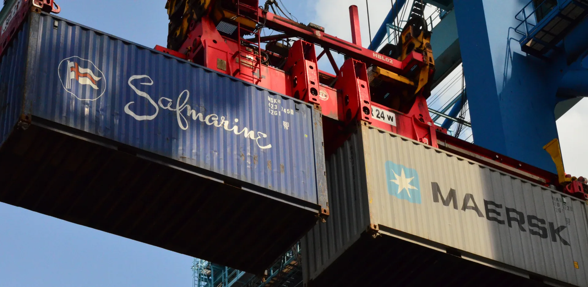 two containers in the air, lifted by a crane